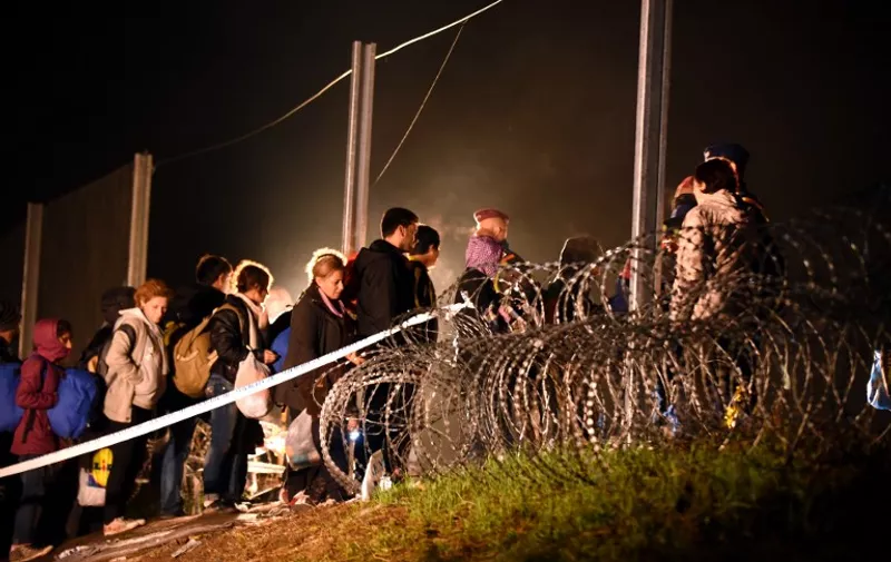 Migrants arriving from Tovarnik cross the border to Hungary before Hungarian police and soldiers closed the border with barbed wire in Botovo on October 16, 2015.  The border between Hungary and Croatia has been closed to "illegal" migrants, the Hungarian government said, with barbed wire fences being set up to seal the frontier. Earlier in the day Croatia announced that it would divert migrants to Slovenia after Hungary said it would close the border with its fellow EU member -- a major transit point for tens of thousands of refugees -- at midnight.  AFP PHOTO/STR / AFP PHOTO / STR