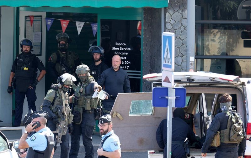 French gendarms and elite police tactical unit of the National Gendarmerie of France (GIGN) stand outside a bank, where a man killed a person and took customers hostage, in La Possession commune on the French Indian Ocean island of La Reunion on October 28, 2023. In the early morning, a man stabbed his mother and then his niece to death before going to a Crédit Agricole bank branch where he killed a person and took customers hostage. He was arrested shortly after, according to the gendarmerie. (Photo by Richard BOUHET / AFP)
