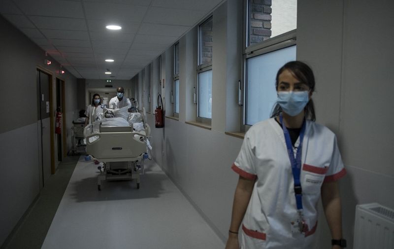 Medical staff members transport a Covid-19 patient under respiratory assistance, at the Andre - Gregoire hospital in Montreuil, east of Paris, on December 14, 2021. (Photo by JULIEN DE ROSA / AFP)