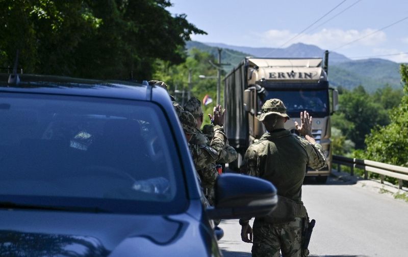 NATO soldiers greet a truck driver near the town of Zubin Potok on August 1, 2022. - Serbs in North Kosovo removed barricades on August 1 that closed two crossings along the border with Serbia after authorities in Pristina postponed the implementation of new travel measures that sparked tensions. Trucks and barriers were being cleared from the roads, according to an AFP reporter, hours after a string of shootings and air raid sirens in northern Kosovo sent tensions soaring in the disputed territory home to both Serbs and ethnic Albanians. (Photo by Armend NIMANI / AFP)