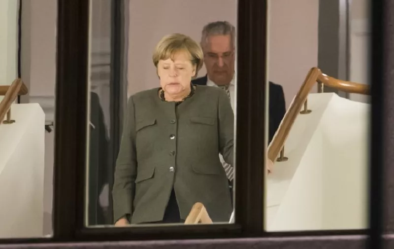 German Chancellor and leader of the Christian Democratic Union (CDU) party, Angela Merkel (L) and Interior Minister of the State of Bavaria Joachim Herrmann are seen coming down a staircase during a break in exploratory talks to form a new government on November 17, 2017 in Berlin. / AFP PHOTO / Odd ANDERSEN