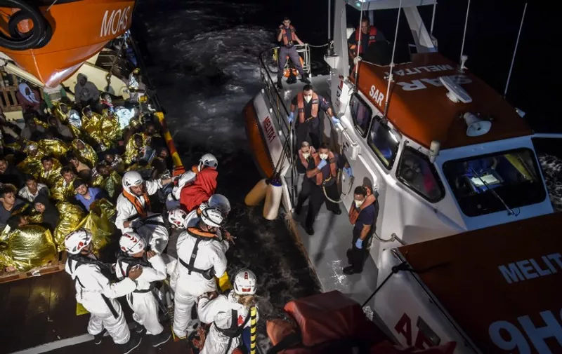 A sick man rescued with a group of migrants and refugees off the Libyan coast is transferred by members of NGO MOAS and doctors of the Red Cross from the Topaz Responder ship, to a boat of Malta's Coast Guards to receive medical assistance on November 6, 2016, while sailing to the port of La Valletta, Malta.  / AFP PHOTO / ANDREAS SOLARO