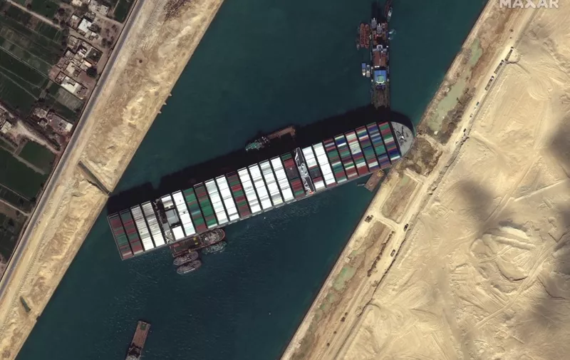 This satellite imagery released by Maxar Technologies shows tug boats and dredgers on March 27, 2021, attempting to free the Taiwan-owned MV Ever Given lodged sideways and impeding all traffic across Egypt's Suez Canal. - The container ship, which is longer than four football fields, has been wedged diagonally across the entire canal since March 23, shutting the waterway in both directions. The blockage has caused a huge traffic jam for more than 200 ships at either end of the 193-km (120-mile) long canal and major delays in the delivery of oil and other products. (Photo by - / Satellite image ©2021 Maxar Technologies / AFP) / RESTRICTED TO EDITORIAL USE - MANDATORY CREDIT "AFP PHOTO / Satellite image ©2021 Maxar Technologies" - NO MARKETING - NO ADVERTISING CAMPAIGNS - DISTRIBUTED AS A SERVICE TO CLIENTS