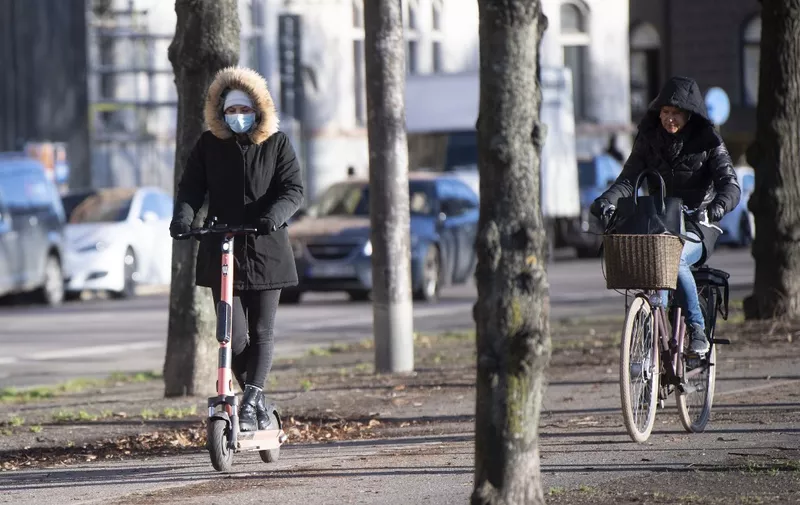 A woman wearing a face mask rides an electric scooter in Stockholm, Sweden, on November 20, 2020, amid the ongoing coronavirus pandemic. (Photo by Fredrik SANDBERG / TT News Agency / AFP) / Sweden OUT