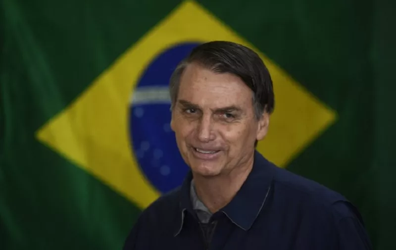 Brazil's right-wing presidential candidate for the Social Liberal Party (PSL) Jair Bolsonaro walks in front of the Brazilian flag as he prepares to cast his vote during the general elections, in Rio de Janeiro, Brazil, on October 7, 2018.
Polling stations opened in Brazil on Sunday for the most divisive presidential election in the country in years, with far-right lawmaker Jair Bolsonaro the clear favorite in the first round. About 147 million voters are eligible to cast ballots and choose who will rule the world's eighth biggest economy. New federal and state legislatures will also be elected. / AFP PHOTO / Mauro PIMENTEL