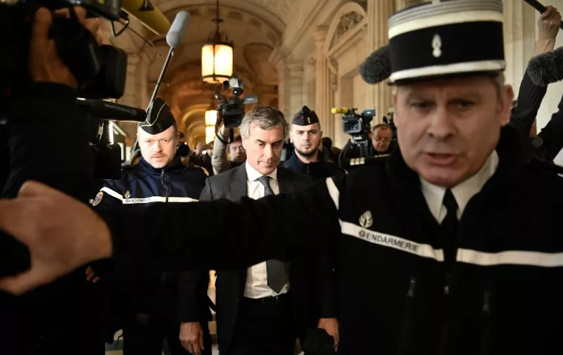 Gendarmes escort French former budget minister Jerome Cahuzac (C) as he leave the Paris courthouse following his tax fraud and money laundering trial's verdict on December 8, 2016. 
Former French budget minister Jerome Cahuzac, whose brief in government was to crack down on tax dodgers, was sentenced to three years in prison on December 8 for tax fraud and money laundering. / AFP PHOTO / PHILIPPE LOPEZ