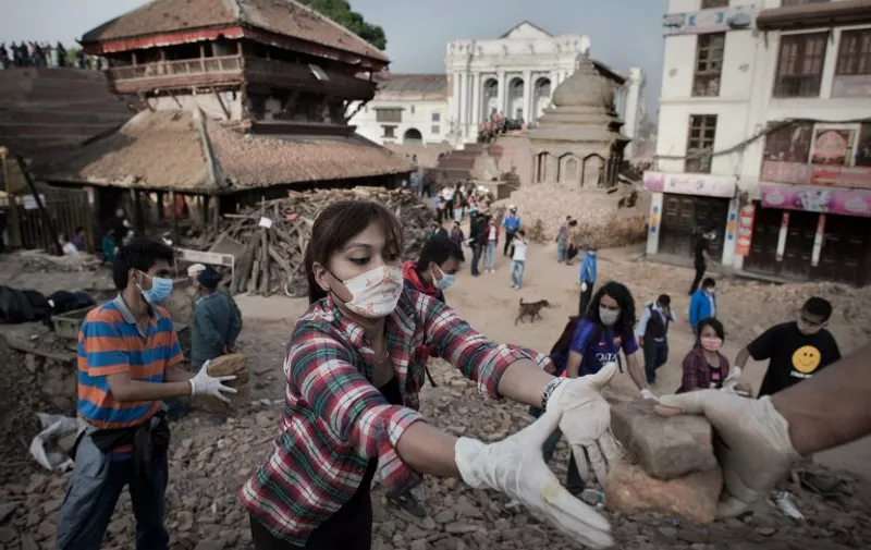 Nepalese people clear rubble at the Basantapur Durbar square in Kathmandu on May 1, 2015, following a 7.8 magnitude earthquake which struck the Himalayan nation on April 25. Desperate survivors living at ground zero of Nepal's earthquake felt abandoned to their fate after losing their loved ones and livelihoods in a disaster that has claimed more than 6,300 lives. AFP PHOTO / Nicolas ASFOURI