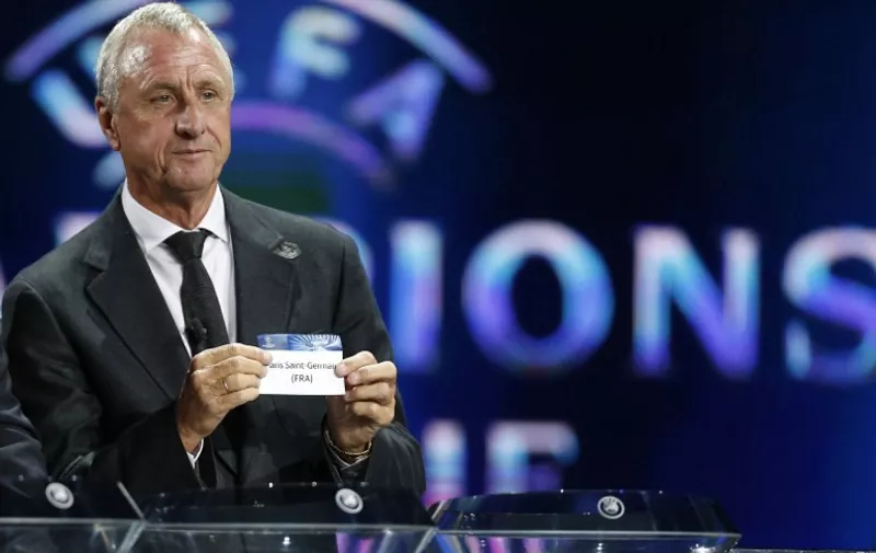 Dutch former football player Johan Cruyff shows a paper reading "Paris Saint-Germain" as he proceeds to the draw of the UEFA 2013/2014 Champions League group stage, on August 29, 2013 in Monaco.    AFP PHOTO / VALERY HACHE