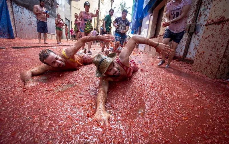 Revellers mock a swim in tomato pulp during the annual "tomatina" festivities in the village of Bunol, near Valencia on August 26, 2015. Some 22,000 revellers hurled 150 tonnes of squashed tomatoes at each other drenching the streets in red in a gigantic Spanish food fight marking the 70th annual "Tomatina" battle.    AFP PHOTO / BIEL ALINO