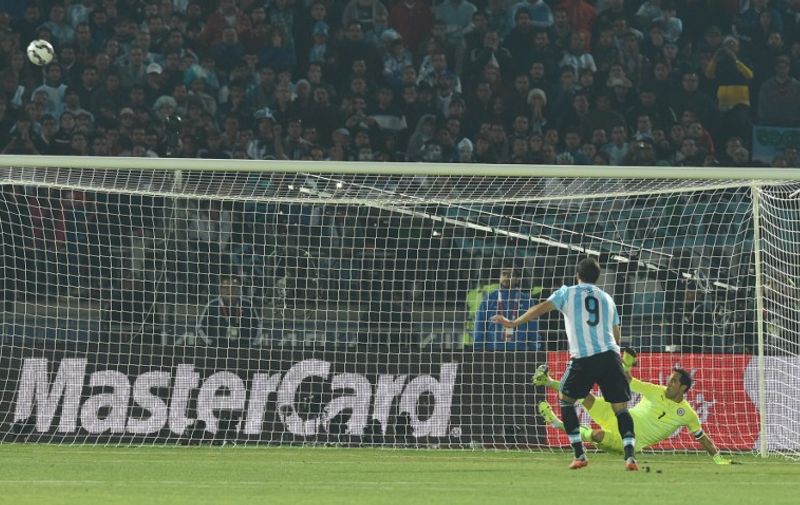 Argentina's forward Gonzalo Higuain (front) kicks the ball over the goal as Chile's goalkeeper Claudio Bravo dives during the penalty shootout of the 2015 Copa America football championship final, in Santiago, Chile, on July 4, 2015.   AFP PHOTO / PABLO PORCIUNCULA