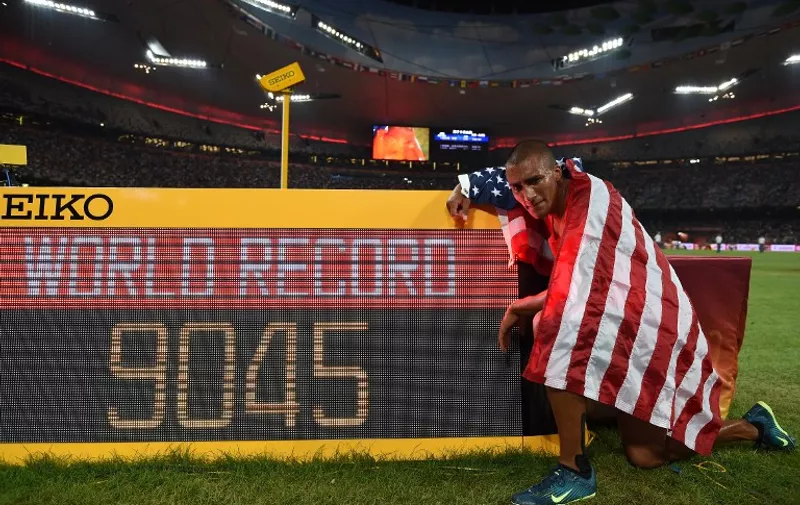 USA's Ashton Eaton poses next to the scoreboard showing Eaton's points total, a new world record, after finishing the 1500 metres and winning the men's decathlon athletics event at the 2015 IAAF World Championships at the "Bird's Nest" National Stadium in Beijing on August 29, 2015. Eaton set a new decathlon world record of 9045 points.   AFP PHOTO / FRANCK FIFE