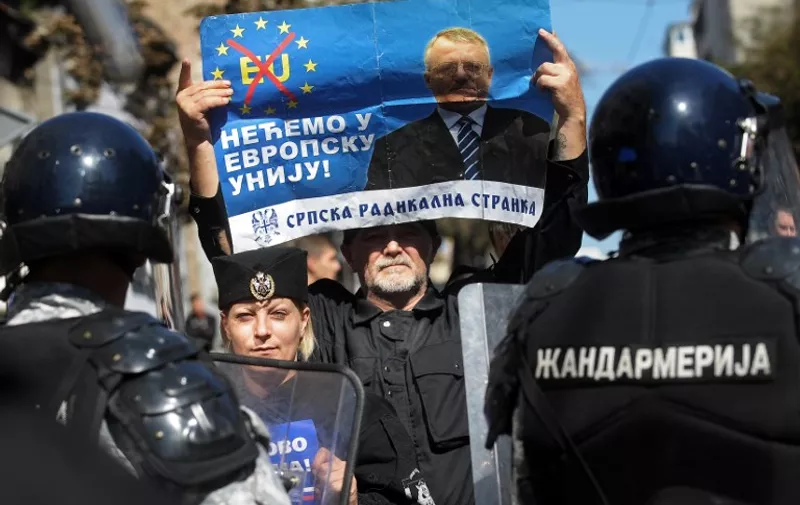Serbian ultra-nationalists hold a banner showing Serbian Radical Party leader Vojislav Seselj reading "We don't want to join the EU" during a protest against the Pride Parade in Belgrade on September 28, 2014. Serbian gays and lesbians staged their first Belgrade Pride Parade in four years on Sunday, in what is seen as a test of the EU hopeful's commitment to protecting minority rights. With tight security, the march went off without incident, led off from the main government building, with hundreds of participants carrying rainbow-colored balloons and flags, and banners proclaiming "Pride", "Peace" and "Love".   AFP PHOTO / ALEXA STANKOVIC