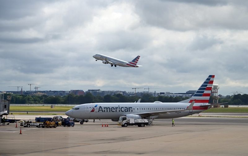 (FILES) In this file photo an American Eagle plane takes off while an American Airlines plane approaches a gate at Ronald Reagan Washington National Airport on July 10, 2020, in Arlington, Virginia, during the coronavirus pandemic. - American Airlines said on August 25, 2020 it will lay off 19,000 workers on October 1, in addition to thousands more who left the company or agreed to voluntary furloughs, unless Congress offers more aid. "Approximately 19,000 of our team members will be involuntarily furloughed or separated from the company on October 1," American said in a regulatory filing, explaining the cuts are needed because flights have not recovered amid the coronavirus pandemic. (Photo by Daniel SLIM / AFP)