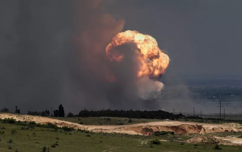 A picture shows detonation of ammunition caused by a fire at a military training field in the Kirovsky district of Crimea on July 19, 2023. Russian President Vladimir Putin has been informed about a fire at a military site in Moscow-annexed Crimea that forced authorities to evacuate thousands of civilians on July 19, 2023, the Kremlin said. News of the blaze came two days after Ukraine used waterborne drones to attack the Kerch bridge, a key military supply artery from mainland Russia to annexed Crimea. Authorities ordered the evacuation of over 2,000 residents from areas near the military field. A section of the Tavrida highway -- connecting the eastern Crimean port of Kerch to the port of Sevastopol on the peninsula's Black Sea coast -- was closed due to the fire. (Photo by Viktor KOROTAYEV / Kommersant Photo / AFP) / Russia OUT