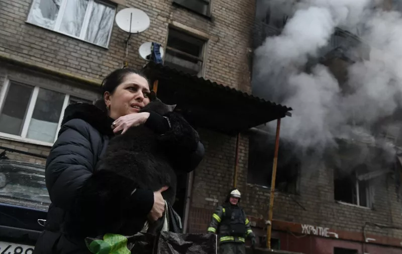 A woman reacts holding her cat, which was found by firefighters in a damaged multi-storey residential building hit by recent shelling in Donetsk, Russian-controlled Ukraine, amid the Russia-Ukraine conflict on December 19, 2023. (Photo by STRINGER / AFP)