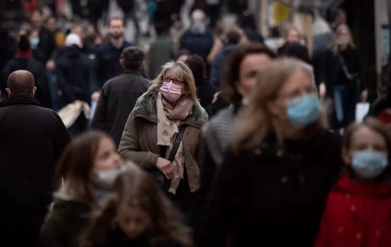 People wearing face masks walk down a street in Nantes, western France, on December 31, 2021. - Since December 31, 2021, the face mask is mandatory again in the streets to prevent the spread of the Covid-19 (coronavirus) pandemic. (Photo by LOIC VENANCE / AFP)