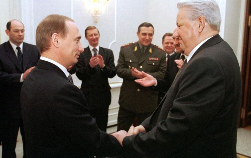 Russian President Boris Yeltsin (R) shakes hands with Prime Minister Vladimir Putin (L) during a farewell ceremony in Kremlin in Moscow, as members of the Presidential administration and the government look on and applaud 31 December 1999. Boris Yeltsin earlier today announced that he was resigning immediately and that Vladimir Putin, according to the Russian Constitution, would run the country as acting President until presidential elections in March 2000.        / AFP PHOTO / ITAR-TASS