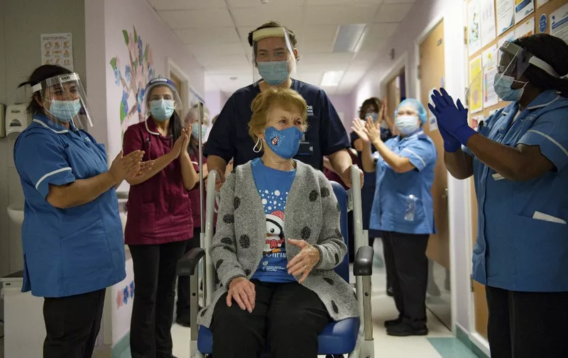 Margaret Keenan (C), 90, is applauded by staff as she returns to her ward after becoming the first person to receive the Pfizer-BioNtech Covid-19 vaccine at University Hospital in Coventry, central England, on December 8, 2020. - Britain on December 8 hailed a turning point in the fight against the coronavirus pandemic, as it begins the biggest vaccination programme in the country's history with a new Covid-19 jab. (Photo by Jacob King / POOL / AFP)
