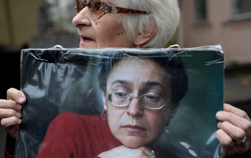 A woman holds a portrait of slain Russian journalist Anna Politkovskaya during a rally marking the 10th anniversary of her murder in Moscow on October 7, 2016. - Rights groups mark a decade since the murder of investigative journalist Anna Politkovskaya who fiercely criticised the Kremlin's tactics in the wars in Chechnya. (Photo by Natalia KOLESNIKOVA / AFP)