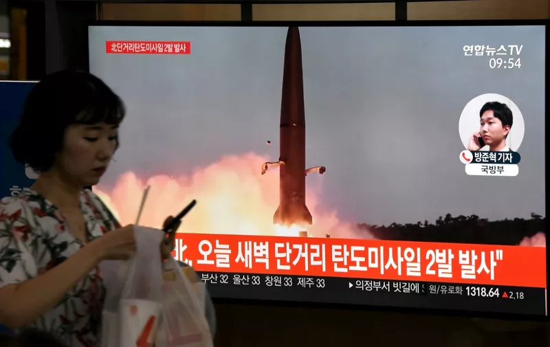 A woman walks past a television news screen showing file footage of a North Korean missile launch, at a railway station in Seoul on July 31, 2019. - Pyongyang fired two ballistic missiles on July 31, Seoul said, days after a similar launch that the nuclear-armed North described as a warning to the South over planned joint military drills with the United States. (Photo by Jung Yeon-je / AFP)