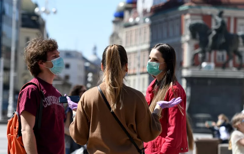 People wearing face masks on April 17, 2020 stand in central Zagreb during the COVID-19 pandemic, cause by the new coronavirus. (Photo by DENIS LOVROVIC / AFP)