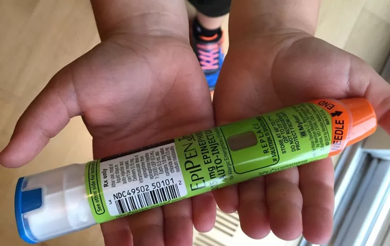 (FILES) This file photo taken  August 24, 2016 photo taken in Hudson, Wisconsin shows a youngster holding Epipens, that he uses to counteract allergic reactions.
The drugmaker Mylan NV said August 29, 2016 it would offer a generic version of the EpiPen, the company's second move in a week to contain public outrage over perceived price gouging. A five-fold increase in the price of the life-saving epinephrine injectors over a decade drew stinging rebukes last week, with Democratic presidential nominee Hillary Clinton and others demanding the company drop its prices. Mylan, which holds a virtual monopoly on the devices that allergy sufferers use to treat potentially deadly anaphylactic shocks, said the generic version would have a list price of $300, a discount of more than half.
 / AFP PHOTO / Lucas TRIEB
