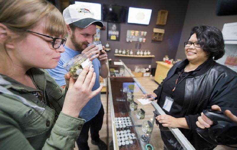 Tourists Laura Torgerson and Ryan Sheehan, visiting from Arizona, smell cannabis buds at the Green Pearl Organics dispensary on the first day of legal recreational marijuana sales in California, January 1, 2018 in Desert Hot Springs, California. / AFP PHOTO / Robyn Beck