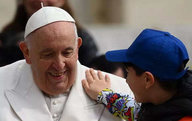 A boy pats Pope Francis on the shoulder while leaving in the popemobile car on March 29, 2023 at the end of the weekly general audience at St. Peter's square in The Vatican. (Photo by Vincenzo PINTO / AFP)