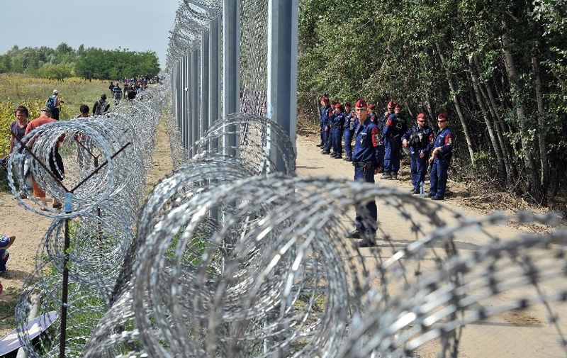 TOPSHOTS
Migrants and refugees walk near razor-wire along a 3-meter-high fence secured by Hungarian police (R) at the official border crossing between Serbia and Hungary, near the northern Serbian town of Horgos on September 15, 2015. Hungary effectively sealed its border with Serbia on September 15 to stem the massive influx of refugees as Germany slammed the "disgraceful" refusal of other EU countries to accept more migrants after 22 died in yet another shipwreck. AFP PHOTO / ELVIS BARUKCIC