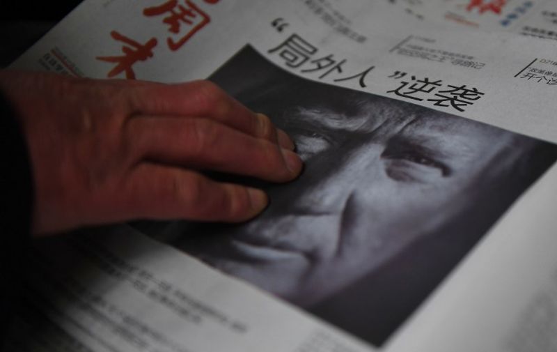 (FILES) This file photo taken on November 10, 2016 shows a man buying a newspaper featuring a photo of US President-elect Donald Trump, the day after the US election, at a news stand in Beijing on November 10, 2016. 
 The headline reads "Outsider strikes back".  President-elect Donald Trump broke with decades of cautious US diplomacy on December 2 to speak with the president of Taiwan, at the risk of provoking a serious rift with China. / AFP PHOTO / GREG BAKER