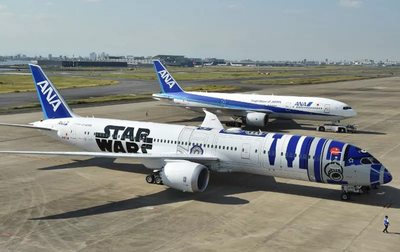 An All Nippon Airways (ANA) Boeing 787-9 aircraft in the livery of Star Wars droid character R2-D2 (front) is seen on the tarmac at Tokyo's Haneda airport on October 14, 2015, as part of the company's Star Wars project. The Boeing aircraft is scheduled to go into service on international routes after a fan appreciation flight event on October 17.    AFP PHOTO / KAZUHIRO NOGI