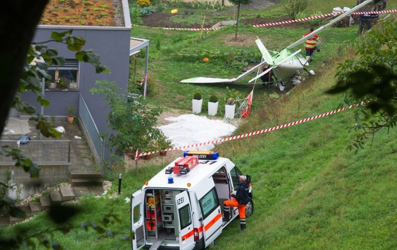 Swiss police officers inspect the wreckage of a plane involved in a collision with a second plane during an airshow on August 23, 2015 in Dittingen, near Basel, northern Switzerland. According to a Swiss news agency, a pilot died and the second pilot --both from the Wurttemberg state in Germany-- managed to eject and parachute himself to land safely. AFP PHOTO / SEBASTIEN BOZON