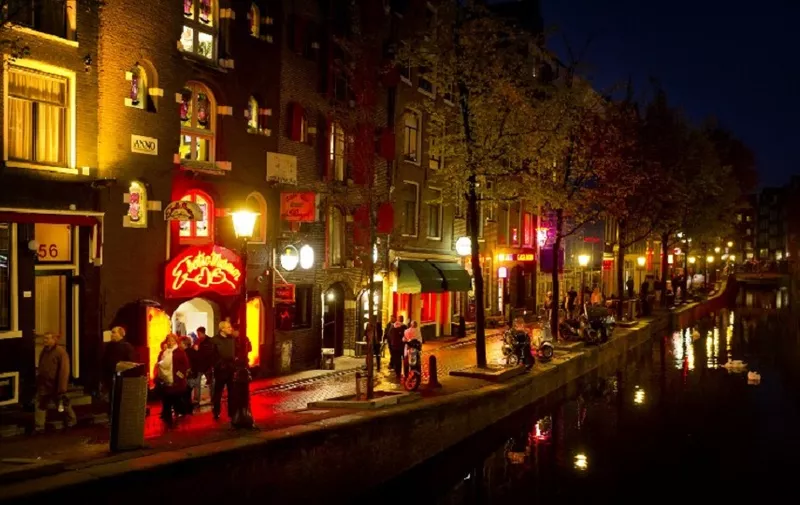 People walk through the red-light district, known as De Wallen, in Amsterdam, on October 13, 2011. De Wallen is the largest red-light district situated in the centre of Amsterdam and a major tourist attraction. The local city government of Amsterdam has initiated a project to buy real estate in the neighborhood to diversify businesses and decrease crime. AFP PHOTO / ANP / KOEN VAN WEEL   ***Netherlands out - Belgium out*** / AFP PHOTO / ANP / Koen van Weel