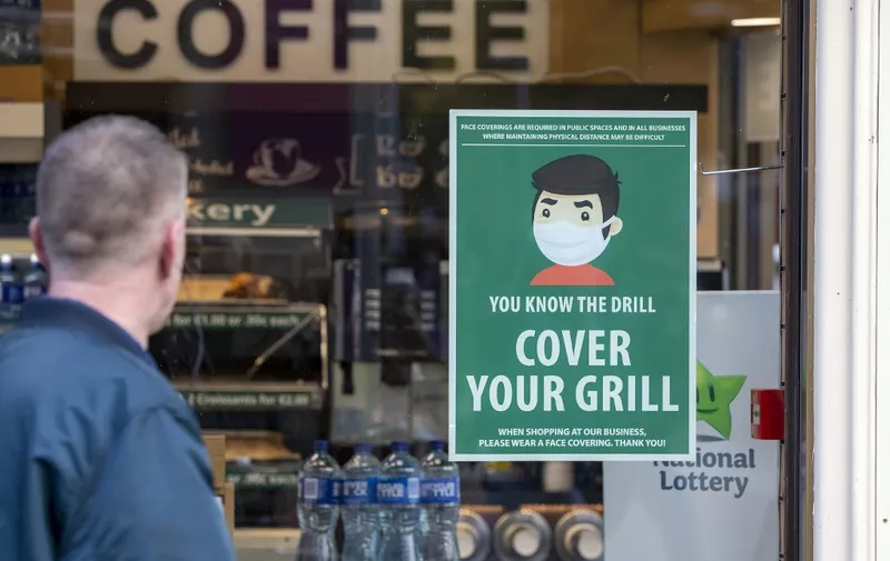 An information poster advising the wearing of face coverings as a precaution against the spread of the novel coronavirus covid-19 is seen on the window of a coffee shop in Dublin on October 21, 2020 as Ireland prepares to enter a second national lockdown to stem the spread of the virus that causes Covid-19. - Millions of people in Ireland were getting set for a second national lockdown on October 21, the first European country to take the drastic step as the continent battles a persistent surge in coronavirus cases. (Photo by Paul Faith / AFP)