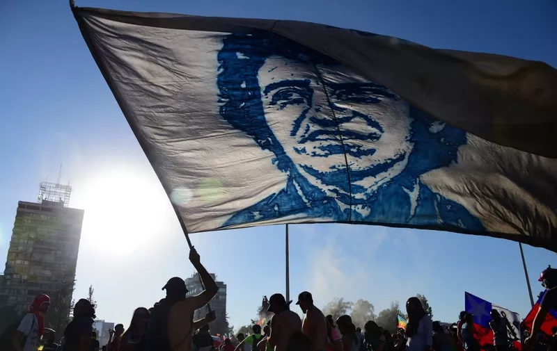 A demonstrator flutters a flag depicting Chilean musician Victor Jara during a protest against the government in Santiago on November 15, 2019. Chile announced Friday it will stage a referendum to replace the country's dictatorship-era constitution -- a key demand of protesters after nearly a month of sometimes violent civil unrest. (Photo by Johan ORDONEZ / AFP)