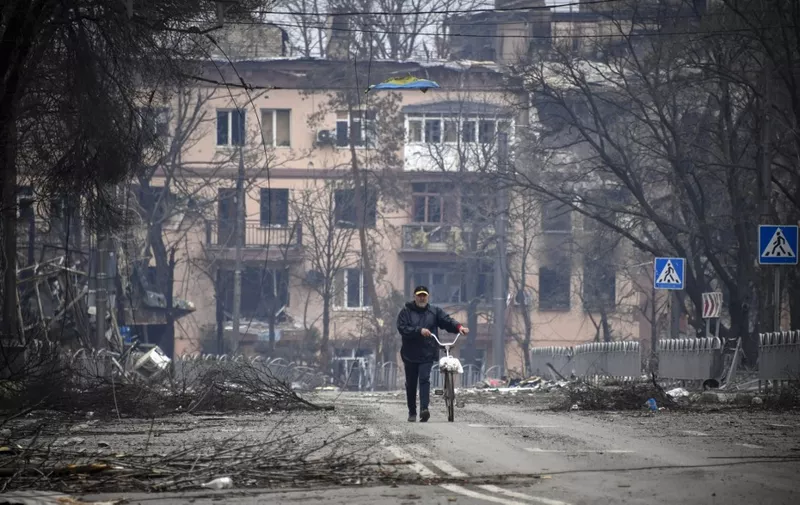 A man walks with a bicycle in downtown Mariupol on April 12, 2022, as Russian troops intensify a campaign to take the strategic port city, part of an anticipated massive onslaught across eastern Ukraine, while Russia's President makes a defiant case for the war on Russia's neighbour. - *EDITOR'S NOTE: This picture was taken during a trip organized by the Russian military.* (Photo by Alexander NEMENOV / AFP)