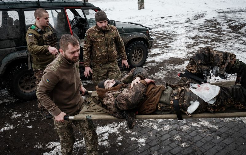 Paramedics carry an injured Ukrainian serviceman who stepped on an anti-personnel land mine at a stabilization point for emergency treatment before sending him to a hospital near the frontline in the Donetsk region on January 29, 2023, amid the Russian invasion of Ukraine. (Photo by YASUYOSHI CHIBA / AFP)