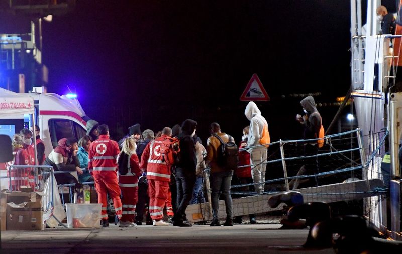 This photo taken overnight on November 6, 2022 and obtained from Italian news agency Ansa, shows migrants disembarking from the rescue ship "Humanity 1" of German organisation SOS Humanity, in Catania, Sicily. - 144 rescued migrants out of 179 have been allowed to disembark to be medically examined in Catania from "Humanity 1", which has been waiting for a safe harbour for two weeks. (Photo by Orietta SCARDINO / ANSA / AFP) / Italy OUT
