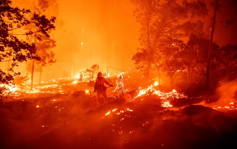 A firefighter works the scene as flames push towards homes during the Creek fire in the Cascadel Woods area of unincorporated Madera County, California on September 7, 2020. - A firework at a gender reveal party triggered a wildfire in southern California that has destroyed 7,000 acres (2,800 hectares) and forced many residents to flee their homes, the fire department said Sunday. More than 500 firefighters and four helicopters were battling the El Dorado blaze east of San Bernardino, which started Saturday morning, California Department of Forestry and Fire Protection (Cal Fire) said. (Photo by JOSH EDELSON / AFP)