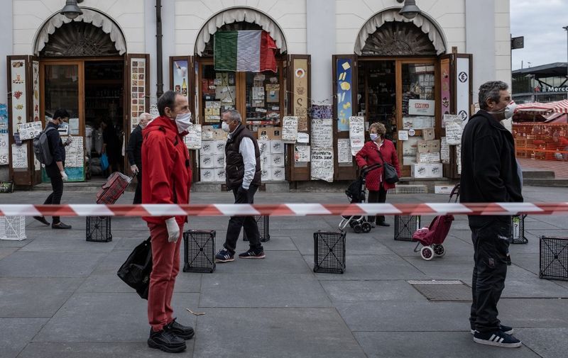 People wait in line at a safety distance to shop at the food market of Porta Palazzo in Turin on May 4, 2020, as Italy starts to ease its lockdown, during the country's lockdown aimed at curbing the spread of the COVID-19 infection, caused by the novel coronavirus. - Stir-crazy Italians will be free to stroll and visit relatives for the first time in nine weeks on May 4, 2020 as Europe's hardest-hit country eases back the world's longest nationwide coronavirus lockdown. (Photo by MARCO BERTORELLO / AFP)