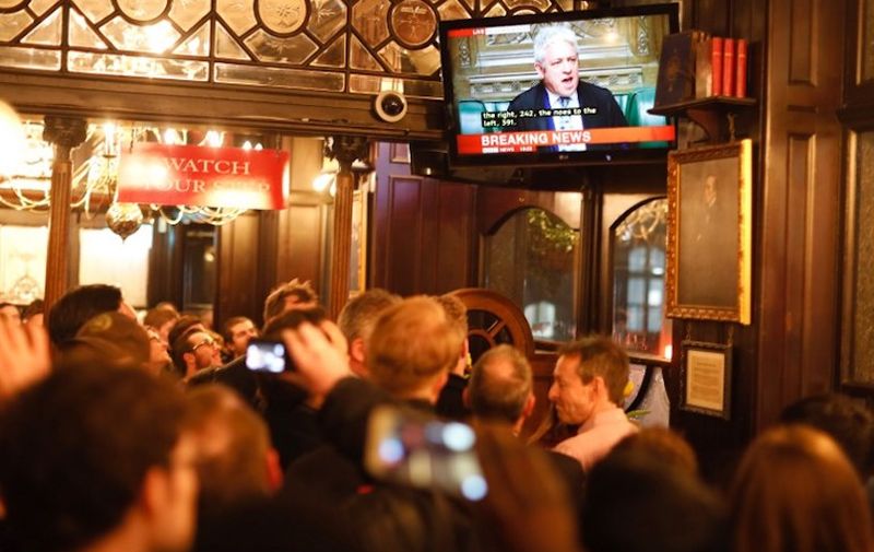 Drinkers watch a television screen in a pub in Whitehall as John Bercow, Speaker of the House declares that Prime Minister Theresa May's Brexit deal was defeated by 149 votes in an historic parliamentary vote on March 12, 2019. (Photo by Tolga AKMEN / AFP)