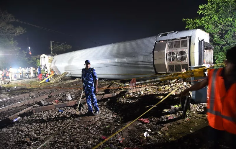 Emergency personnel stand next to an overturned train carriage near Raghunathpur railway station some 44 Km from Buxar on October 12, 2023, after an express train derailed late on October 11 in India's Bihar state. At least four people have been killed and an unknown number injured after an express train derailed in India's Bihar state, local media reported on October 12. (Photo by Sachin KUMAR / AFP)