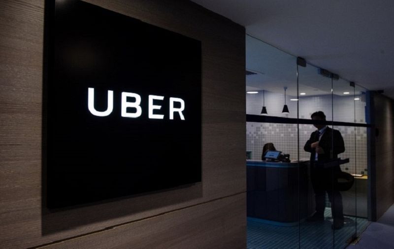 (FILES) This file photo taken on March 10, 2017 shows Uber signage and an employee standing in the entrance of the ride-hailing giant's office in Hong Kong.
Hong Kong police on May 23, 2017 arrested 21 Uber drivers for carrying passengers without a proper permit following an undercover operation in the latest setback for the ride-hailing giant. / AFP PHOTO / Anthony WALLACE