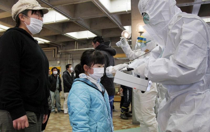 An official in a full radiation protection suit scans an evacuated girl with a geiger counter to check radiation levels in Koriyama city in Fukushima prefecture, about 60km west from the crisis-hit Tokyo Electric Power Co (TEPCO) Fukushima Nuclear plant, on March 16, 2011.  A fresh fire broke out at the quake-hit Japanese atomic power plant in Fukushima early on March 16, compounding Japan's nuclear crisis following the March 11 earthquake and tsunami disaster. AFP PHOTO / Ken SHIMIZU / AFP / KEN SHIMIZU