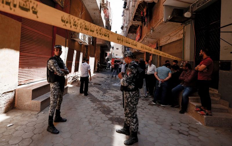 Egyptian police gather outside the Abu Sifin church located in the densely populated Imbaba neighbourhood west of the Nile river, part of Giza governorate, on August 14, 2022, after more than 40 people were killed when a fire ripped through a Coptic Christian church during Sunday mass. Witnesses described how people rushed into the burning house of worship to rescue those trapped but were soon overwhelmed by the heat and the deadly smoke. (Photo by Khaled DESOUKI / AFP)