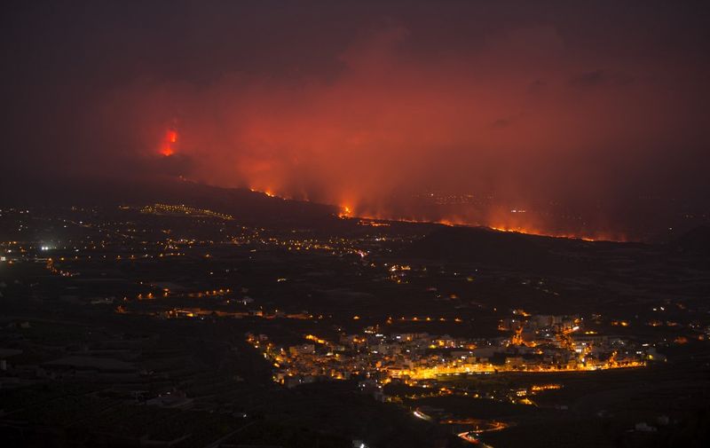 The Cumbre Vieja volcano, pictured at night from La Punta de Tijarafe, spews lava, ash and smoke, in the Canary Island of La Palma on October 7, 2021. - Clouds of thick ash from the erupting volcano on La Palma forced the island's airport to close for the second time since the September 19 eruption. (Photo by JORGE GUERRERO / AFP)