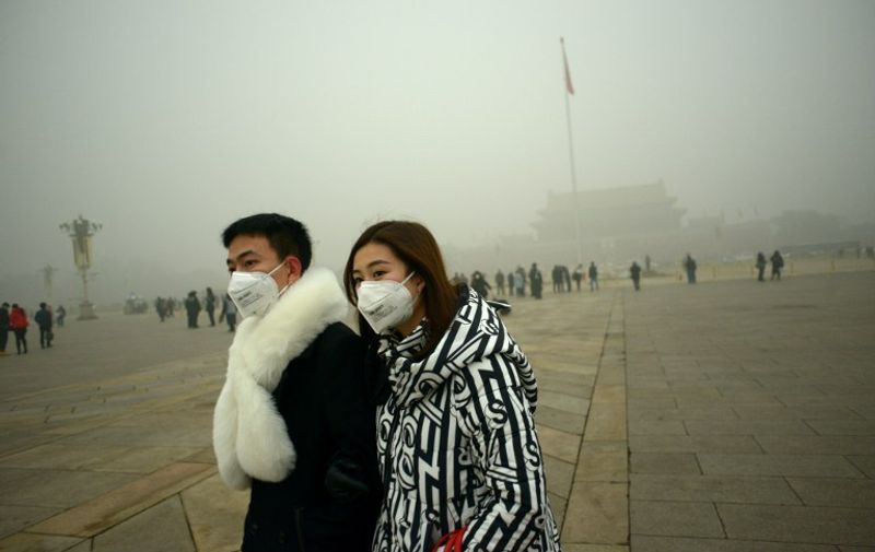 A couple wear masks as they walk in Tiananmen Square during heavy pollution in Beijing on December 1, 2015. Beijing ordered hundreds of factories to shut and allowed children to skip school as choking smog reached over 25 times safe levels on December 1, casting a cloud over China's participation in Paris climate talks.          AFP PHOTO / WANG ZHAO / AFP / Zhao WANG