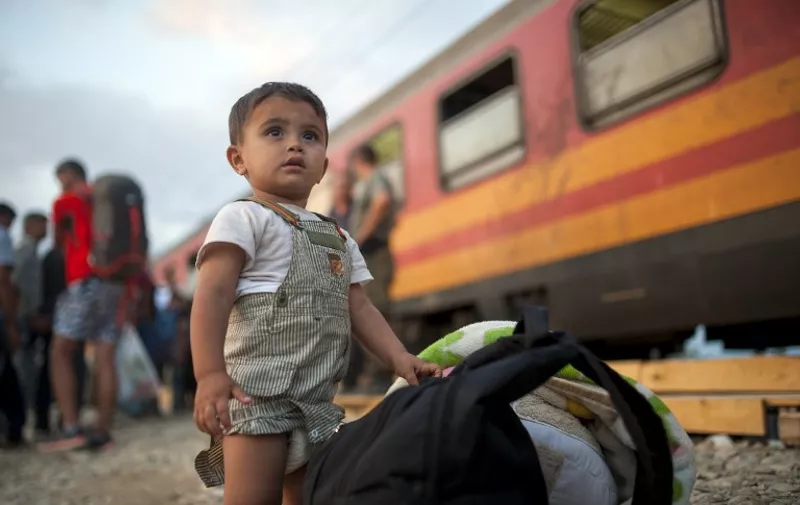 A migrant child stands next to a backpack as he waits to board a train heading to Serbia at the border between Greece and Macedonia near the town of Gevgelija on September 5, 2015. Some 5,600 people crossed into Macedonia from Greece on September 3, a jump that highlights the ever-rising numbers of migrants moving through Europe, the UN said on September 4. More than 245,000 of them have landed in Greece and more than 116,000 in Italy. AFP PHOTO / ROBERT ATANASOVSKI