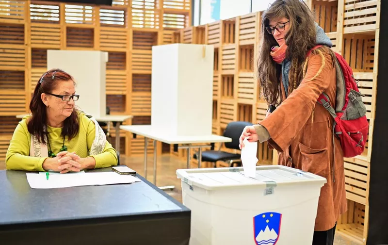 A voter casts her ballot as an electoral official looks on during the run off for Slovenia's Presidential Election at a polling station in Ljubljana on November 13, 2022. - Slovenians are voting in a run-off poll expected to elect the country's first woman president -- a lawyer linked to former US first lady Melania Trump. Natasa Pirc Musar, backed by the centre-left government, is running against ex-foreign minister Anze Logar, a veteran of conservative politics, in the EU country of two million. (Photo by Jure Makovec / AFP)