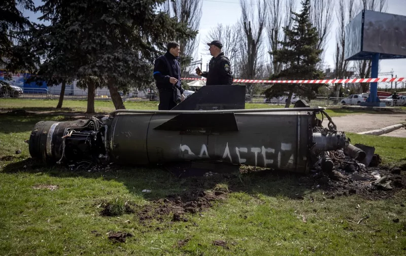 Ukrainian police inspect the remains of a large rocket with the words "for our children" in Russian next to the main building of a train station in Kramatorsk, eastern Ukraine, that was being used for civilian evacuations, that was hit by a rocket attack killing at least 35 people, on April 8, 2022. (Photo by FADEL SENNA / AFP)
